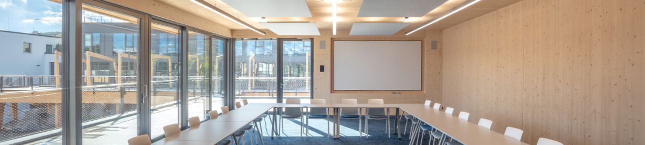 Moderner Besprechungsraum mit Glasfront, Tischen und Leinwand