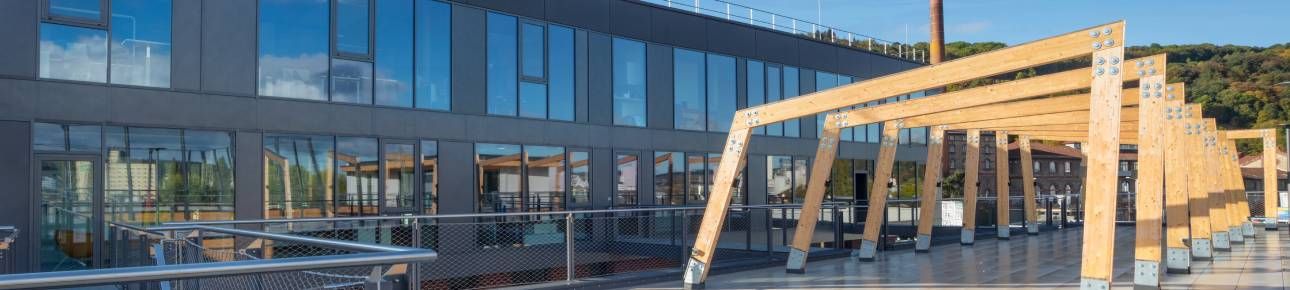 Modernes Bürogebäude von SPRINTIS mit Dachterrasse bei sonnigem Wetter.